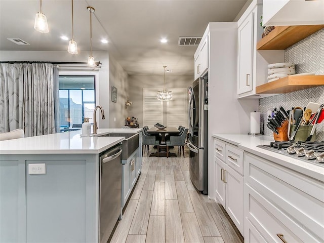 kitchen featuring visible vents, a sink, a kitchen island with sink, and stainless steel appliances