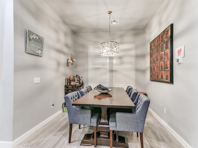dining space with baseboards, light wood-style flooring, a notable chandelier, and visible vents