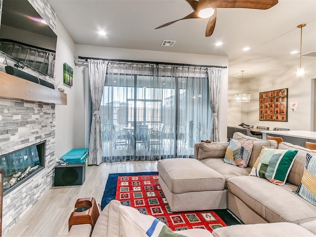 living area featuring a fireplace, a ceiling fan, wood finished floors, and visible vents