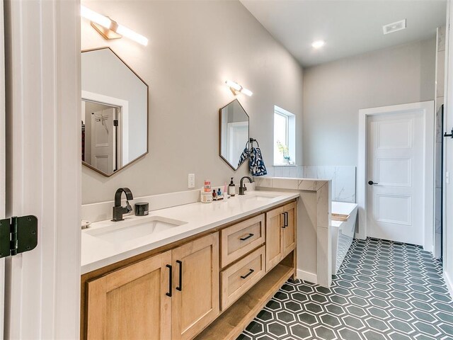 bathroom with double vanity, a sink, a bath, and tile patterned flooring