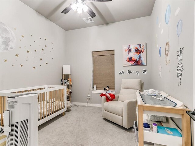 carpeted bedroom featuring a nursery area, baseboards, visible vents, and ceiling fan