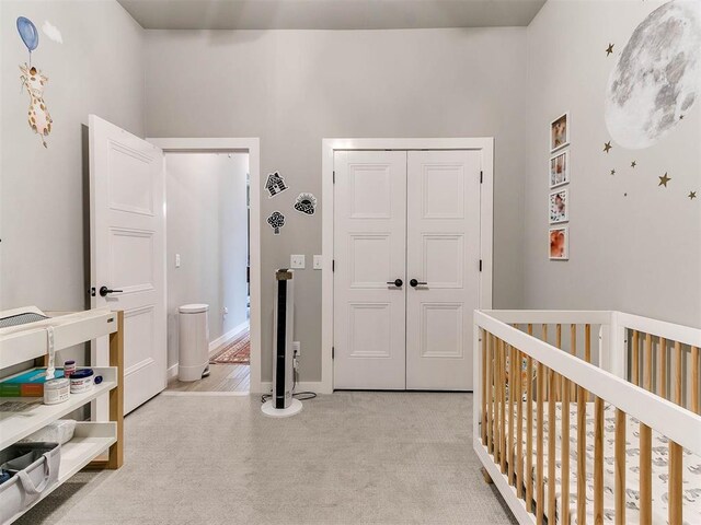 bedroom featuring a closet, a crib, baseboards, and light carpet