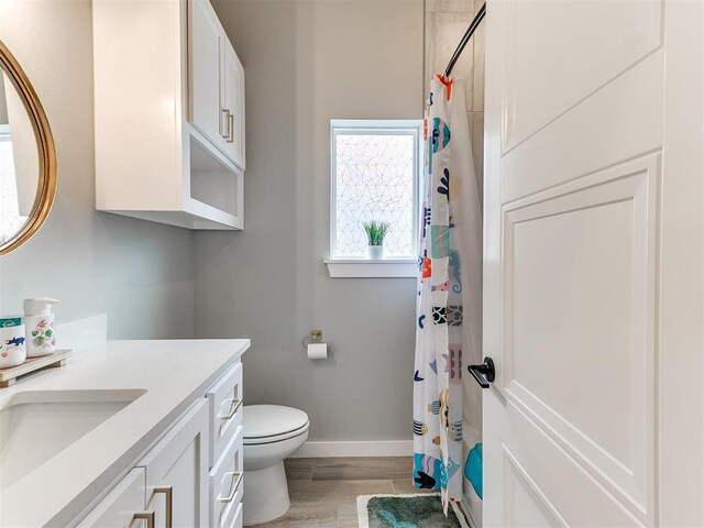bathroom featuring vanity, toilet, a shower with shower curtain, baseboards, and wood finished floors