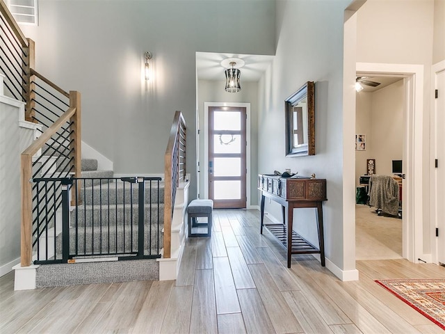 foyer featuring baseboards, wood finished floors, and stairway