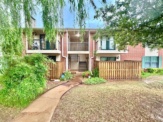 rear view of property featuring brick siding, a chimney, fence, and a balcony