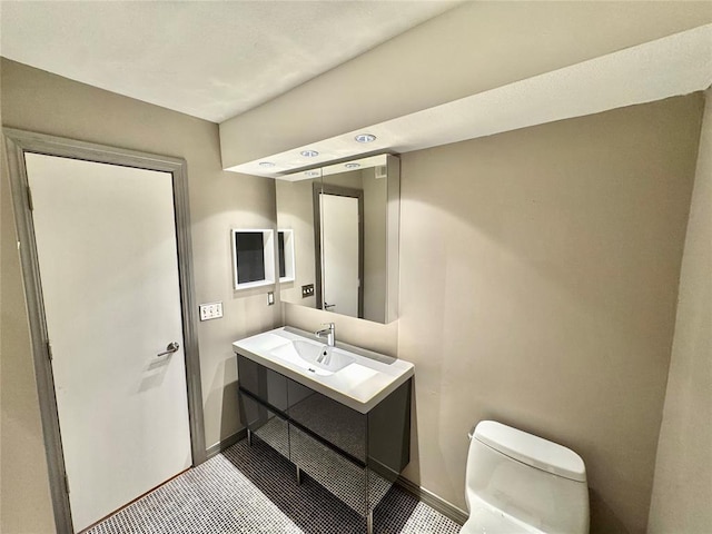 half bathroom featuring vanity, toilet, and baseboards