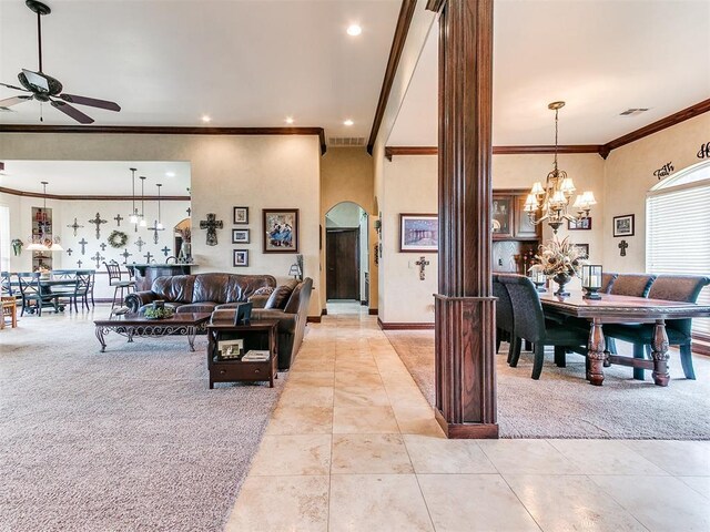 living area with crown molding, light tile patterned flooring, light carpet, arched walkways, and ceiling fan with notable chandelier