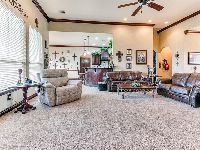 carpeted living area featuring arched walkways, ornamental molding, a ceiling fan, and visible vents