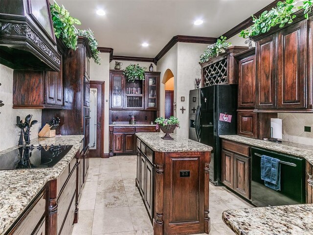 kitchen featuring crown molding, light stone counters, arched walkways, backsplash, and black appliances