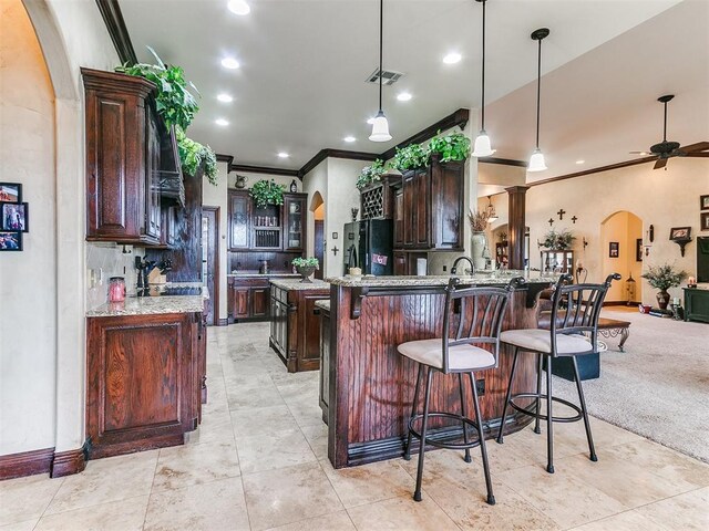 kitchen featuring arched walkways, ornamental molding, freestanding refrigerator, and visible vents
