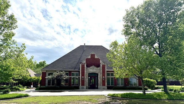 french country style house featuring a front lawn and roof with shingles