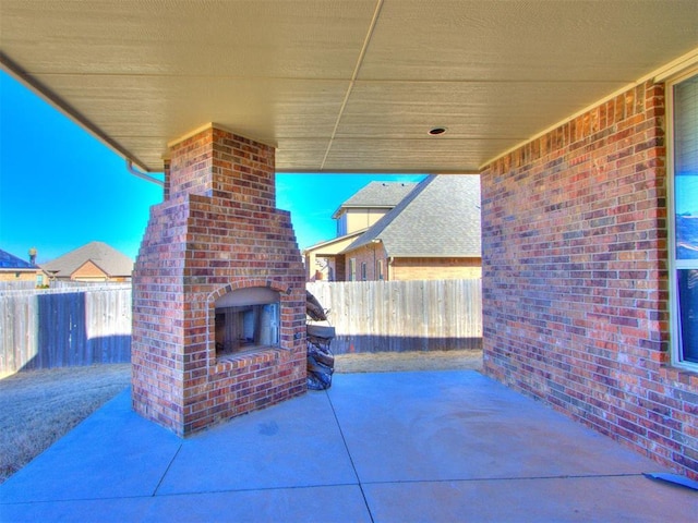 view of patio with a fenced backyard and an outdoor brick fireplace
