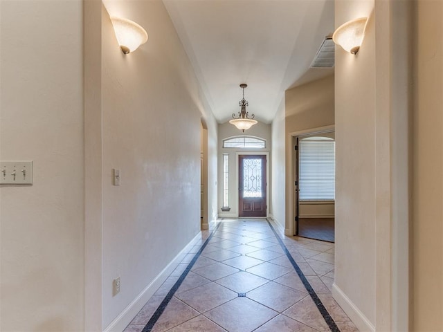 doorway featuring baseboards, arched walkways, light tile patterned flooring, and visible vents