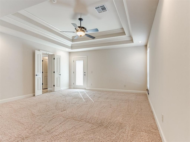 unfurnished room featuring visible vents, carpet flooring, a ceiling fan, and a tray ceiling