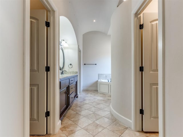 full bath featuring baseboards, tile patterned flooring, a garden tub, and vanity
