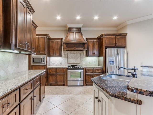 kitchen with appliances with stainless steel finishes, a sink, dark stone counters, custom range hood, and tasteful backsplash