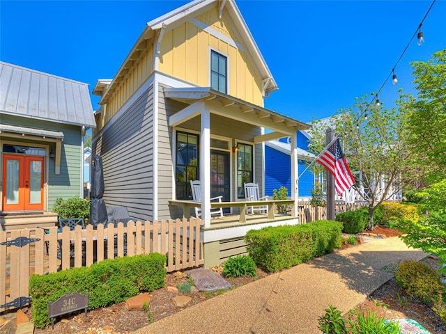 34 Boardwalk Unit B, Carlton Landing, OK 74432 - view of front of house with french doors, board and batten siding, covered porch, and a fenced front yard