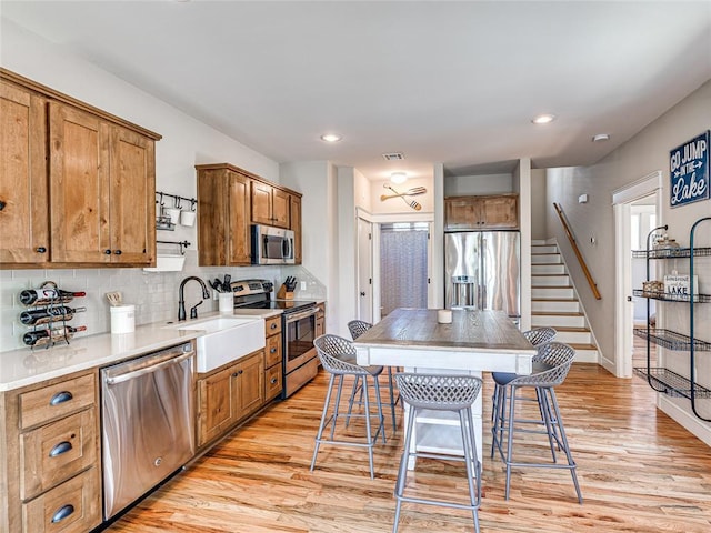 34 Boardwalk Unit B, Carlton Landing, OK 74432 - kitchen featuring brown cabinets, appliances with stainless steel finishes, a sink, light wood finished floors, and decorative backsplash