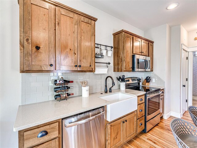 34 Boardwalk Unit B, Carlton Landing, OK 74432 - kitchen featuring appliances with stainless steel finishes, a sink, light wood finished floors, brown cabinetry, and decorative backsplash