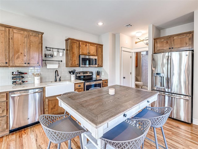 34 Boardwalk Unit B, Carlton Landing, OK 74432 - kitchen featuring appliances with stainless steel finishes, a sink, brown cabinetry, light wood-style flooring, and visible vents