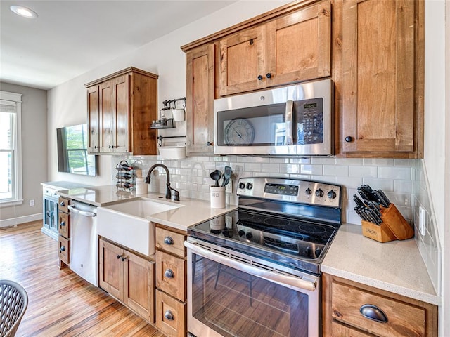 34 Boardwalk Unit B, Carlton Landing, OK 74432 - kitchen featuring brown cabinetry, tasteful backsplash, a sink, light wood finished floors, and appliances with stainless steel finishes