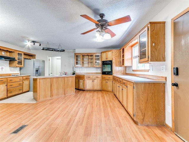11817 Hollyrock Dr, Yukon, OK 73099 - kitchen with oven, under cabinet range hood, a textured ceiling, light wood-type flooring, and open shelves
