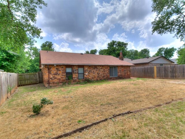 11817 Hollyrock Dr, Yukon, OK 73099 - back of property featuring stone siding and a chimney