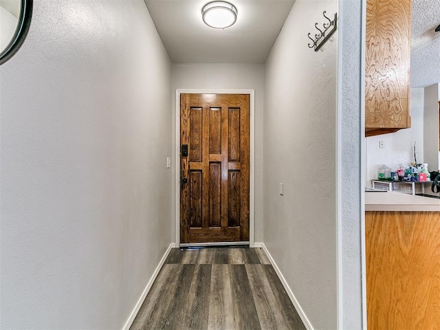 11817 Hollyrock Dr, Yukon, OK 73099 - doorway featuring dark wood-type flooring, baseboards, and a textured wall