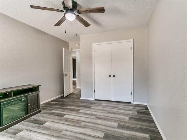 11817 Hollyrock Dr, Yukon, OK 73099 - unfurnished bedroom featuring a textured ceiling, wood finished floors, baseboards, and ceiling fan