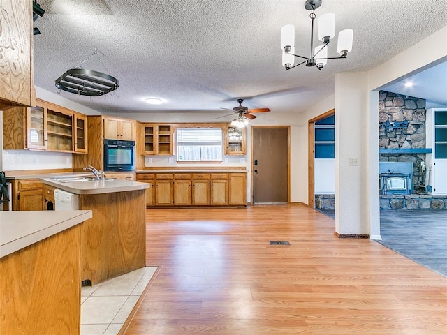 11817 Hollyrock Dr, Yukon, OK 73099 - kitchen featuring oven, a textured ceiling, light countertops, light wood-style floors, and a sink
