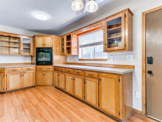 11817 Hollyrock Dr, Yukon, OK 73099 - kitchen featuring black oven, open shelves, light countertops, light wood-style floors, and a textured ceiling