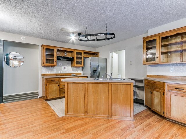 11817 Hollyrock Dr, Yukon, OK 73099 - kitchen featuring stainless steel fridge, open shelves, a sink, light wood-style flooring, and a textured ceiling