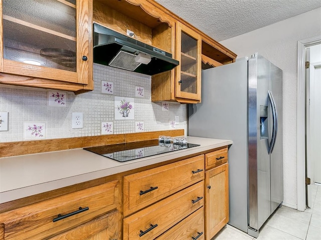 11817 Hollyrock Dr, Yukon, OK 73099 - kitchen with black electric stovetop, under cabinet range hood, stainless steel fridge, backsplash, and brown cabinetry