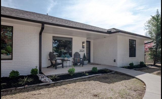 rear view of house featuring a porch and brick siding