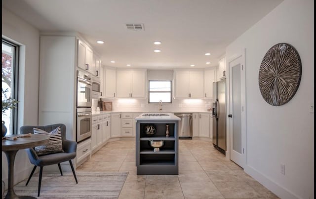 kitchen with light countertops, stainless steel appliances, white cabinets, and visible vents