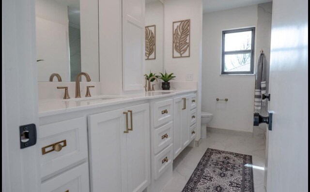 full bath with a sink, toilet, double vanity, and marble finish floor
