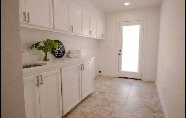 doorway with recessed lighting, baseboards, a sink, and light tile patterned floors