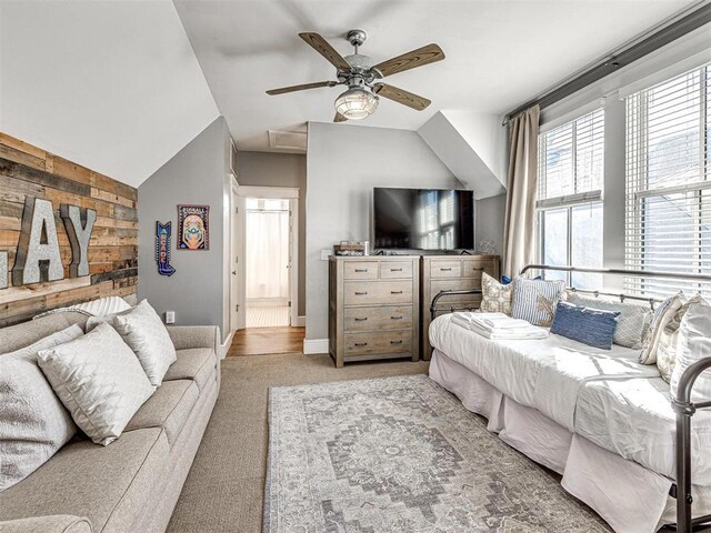 living room with vaulted ceiling, a ceiling fan, wood walls, and light colored carpet