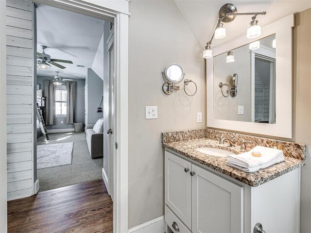 bathroom with ceiling fan, vanity, baseboards, wood finished floors, and vaulted ceiling