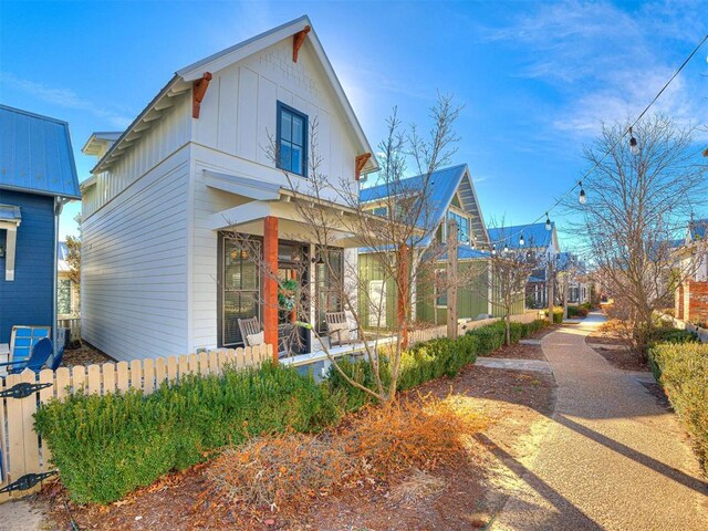 view of front facade with board and batten siding, fence, and covered porch