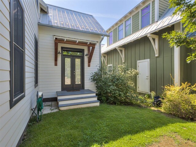 entrance to property featuring board and batten siding, a yard, metal roof, and a standing seam roof