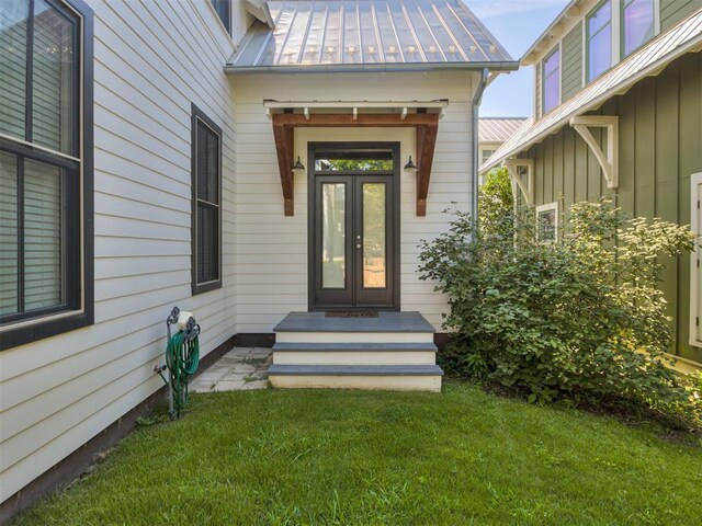 view of exterior entry featuring a yard, a standing seam roof, and metal roof