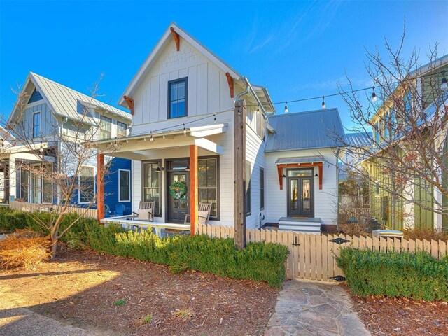 view of front of house featuring a gate, board and batten siding, a fenced front yard, and metal roof