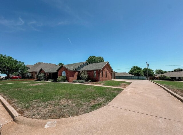 ranch-style home with brick siding, driveway, and a front yard