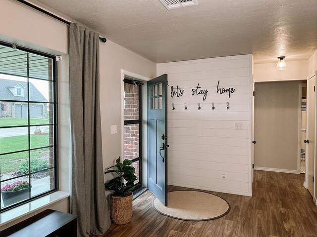 mudroom featuring a textured ceiling, visible vents, dark wood-style floors, and baseboards