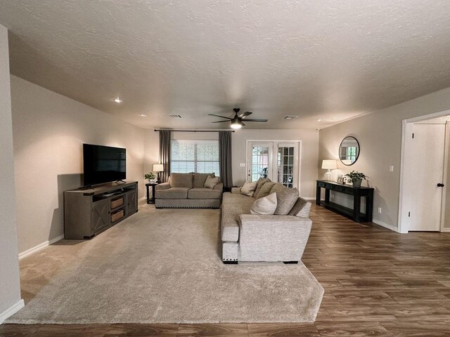 living room featuring baseboards, a ceiling fan, a textured ceiling, and wood finished floors