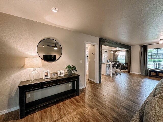 interior space featuring baseboards, a textured ceiling, and wood finished floors