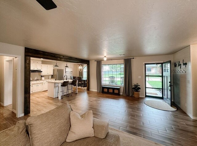 living area with baseboards, a textured ceiling, and wood finish floors