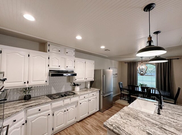 kitchen featuring a sink, freestanding refrigerator, light wood finished floors, black electric stovetop, and under cabinet range hood