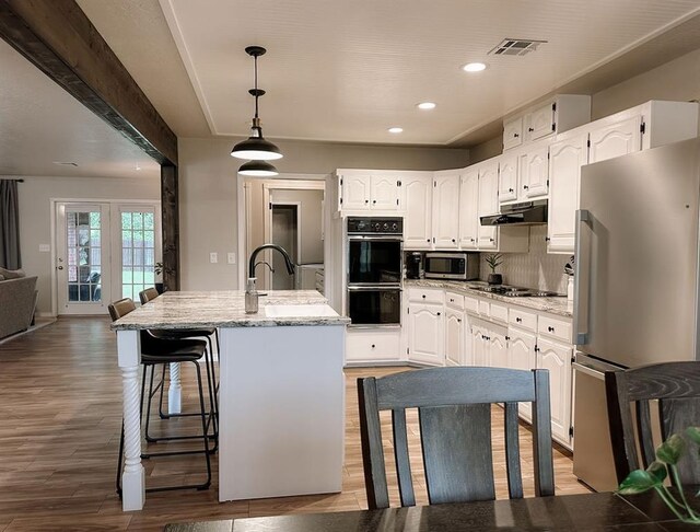 kitchen with white cabinets, recessed lighting, light wood-type flooring, visible vents, and black appliances